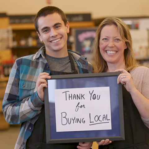 Business Owners holding a Thank you for shopping local sign